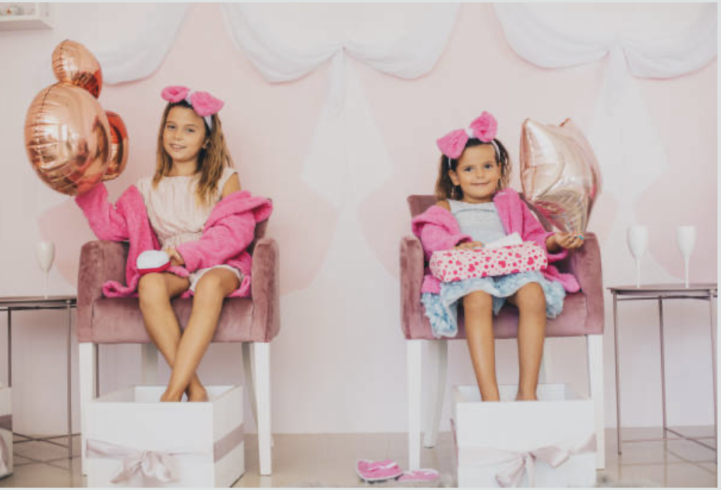 children's spa/pamper party holding birthday ballon, feet in spa bowl 
